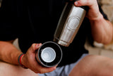 A man holding the Shaker Steel Pour Caddy with removable base, tumbler and shot cups.